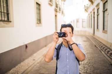 Gülümseyen ve yakışıklı genç Asya seyahat sırt çantası ve kamera ile