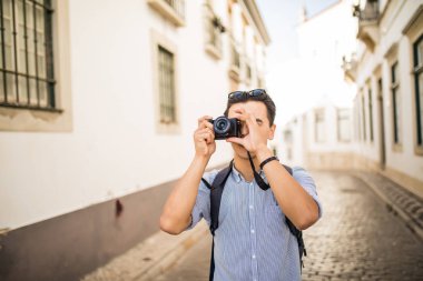 Gülümseyen ve yakışıklı genç Asya seyahat sırt çantası ve kamera ile