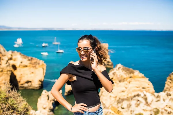 바다 바위 위에 복용 스마트 휴대 전화를 사용 하 여 라틴어 예쁜 여자. 여행 및 활동적인 라이프 스타일 개념 — 스톡 사진