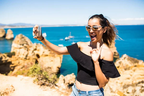 Beauté femme latine prendre selfie du téléphone au sommet de belles falaises et rochers de l'océan Atlantique au Portugal — Photo