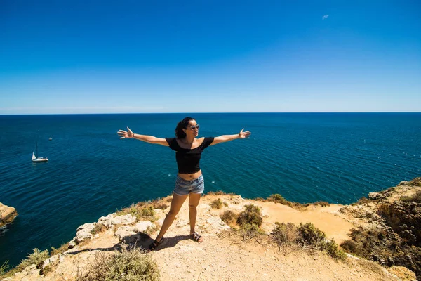 Красивая латинская женщина, стоящая на скале над океаном и приветствует лето — стоковое фото