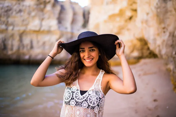 Retrato de bela menina latina na praia com chapéu preto sorriso puro oceano e rochas na vocação de verão — Fotografia de Stock