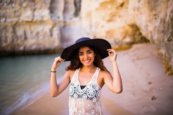 Menina latina bonita usar em chapéu posando na praia perto do oceano na vocação de verão — Fotografia de Stock
