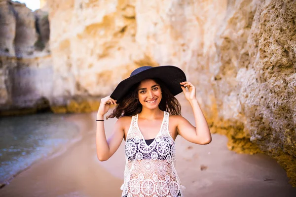 Красива латинська дівчина носить капелюх позує на пляжі біля океану на літнє покликання — стокове фото