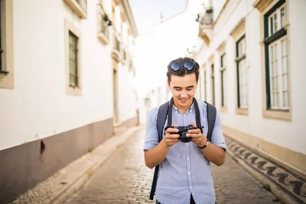 Joven asiático hombre mira taked foto en viajar alrededor de viejo ciudad — Foto de Stock