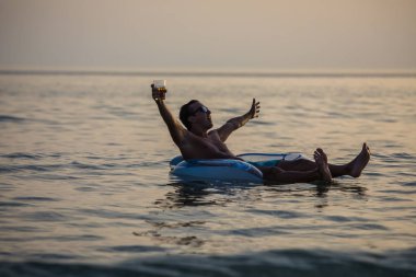 Yükseltilmiş eller gülümseyerek adam ve deniz suyu Kauçuk halka yaz keyfini çıkarın. Yaz meslek.