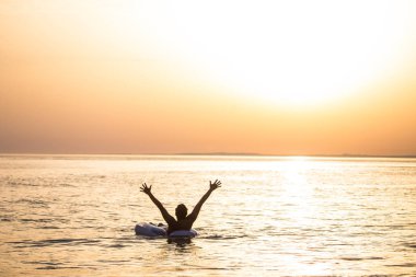 Sunset bulvarında şişme ringde okyanus su üzerinde yüzen kaldırdı elleriyle mutlu genç adam. Adam keyfini yaz meslek eller yukarı okyanus su ile.