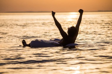 Sunset bulvarında şişme ringde okyanus su üzerinde yüzen kaldırdı elleriyle mutlu genç adam. Adam keyfini yaz meslek eller yukarı okyanus su ile.