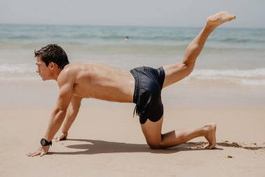 Plajda güneşin egzersizleri yapmak atlet. Plaj eğitim genç adam