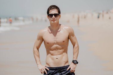 Yakışıklı ve kaslı bir adam sahilde. Yaz saati