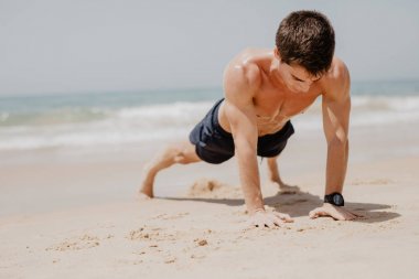 mutlu gülümseyerek push up egzersiz fitness adam. Çapraz Eğitim kumsalda erkek fitness modeli.