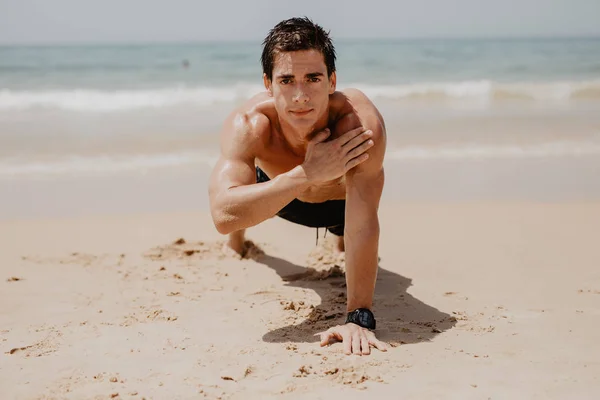 Young man doing push-ups on the ocean beach. — Stock Photo, Image