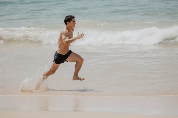 Beach fitness man runner running training cardio. Healthy lifestyle male athlete doing exercise living an active life working out on sunset beach with ocean background topless in shorts. — Stock Photo, Image