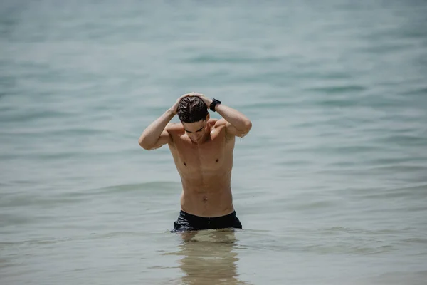 Sexy caucasian fit man posing in a beach in the water — Stock Photo, Image