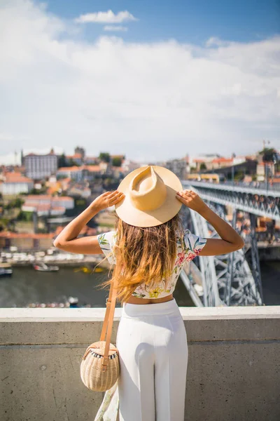 Νεαρά γυναικείο ταξιδιώτη με καπέλο στέκεται και απολαύστε θέα Πόρτο. Πίσω όψη — Φωτογραφία Αρχείου