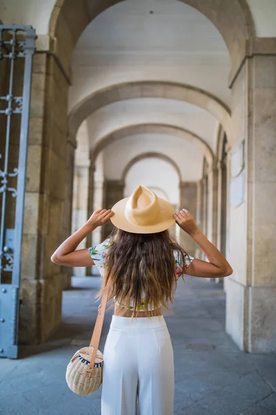 Όμορφη μελαχρινή νεαρή γυναίκα φοράει καπέλο και γυαλιά ηλίου και το περπάτημα σε το δρόμο θερινή ώρα — Φωτογραφία Αρχείου