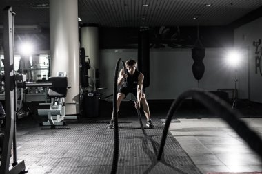 Spor salonunda fitness adam savaş ile çalışma dışarı ipleri. Savaş spor salonu egzersiz donatılmış egzersiz vücut fitness adama ipleri. Savaş ip fitness Club ile eğitim fitness adam. Savaş ip ile eğitim