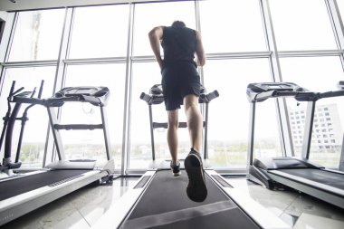 Arkadan görünüşü genç adam atlet spor salonunda koşu bandı üzerinde çalışan ile. Jimnastik.