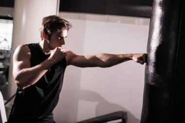 Genç atlet atarak çalışma dışarı içinde jimnastik salonu ağır kum torbası, yumruk atıyor. Eğitim