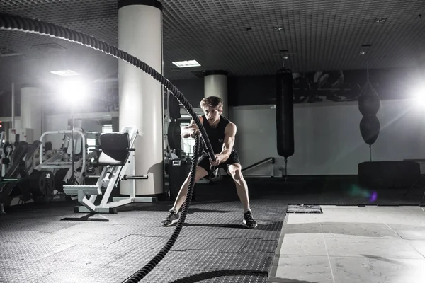 Homem musculoso atraente trabalhando com cordas pesadas. Foto de um homem bonito de fato desportivo. Crossfit — Fotografia de Stock