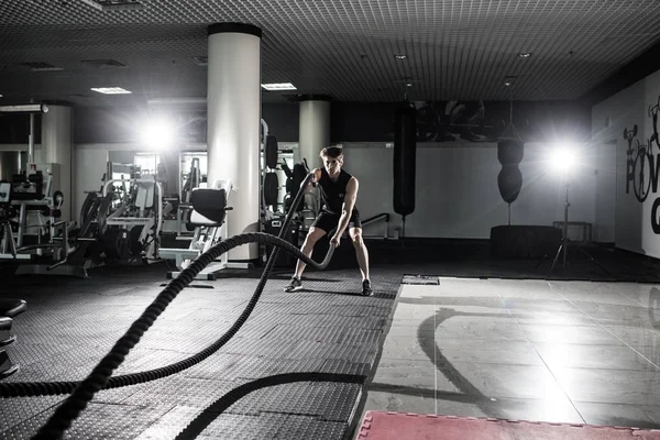 Fitness man working out with battle ropes at gym. Battle ropes fitness man at gym workout exercise fitted body. Fitness man training with battle rope in fitness club. Training with battle rope