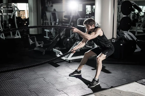 Homem de fitness a treinar com cordas de batalha no ginásio. Homem de fitness cordas de batalha no exercício de ginástica corpo ajustado ginásio. Treinamento de homem de fitness com corda de batalha no clube de fitness. Treinamento com corda de batalha — Fotografia de Stock