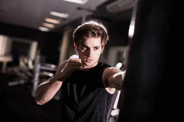 Retrato de boxeador tratando de patear saco de boxeo en el gimnasio durante el entrenamiento. Formación — Foto de Stock