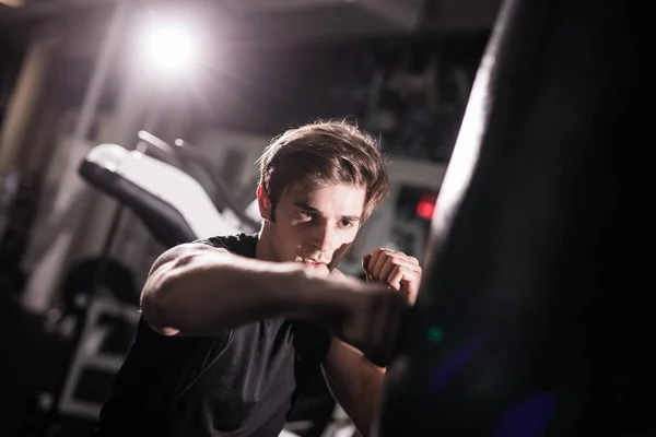 Retrato de boxeador tentando chutar saco de perfuração no ginásio durante o treinamento. Formação — Fotografia de Stock