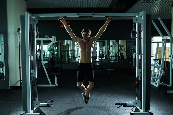 Muito poder atlético cara, executar exercício apertando na barra horizontal, no esporte-hall — Fotografia de Stock