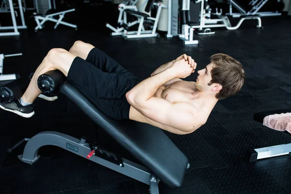 Hombre musculoso ejercitando haciendo ejercicio de sentarse . — Foto de Stock