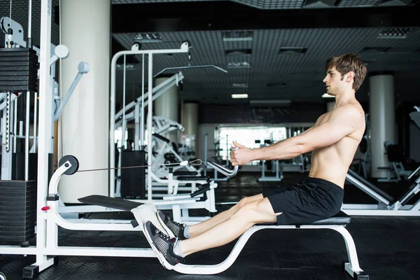 Hombre atlético brutal bombeando músculos en crossover. Musculoso hombre haciendo ejercicio en el gimnasio haciendo ejercicios. gimnasio — Foto de Stock
