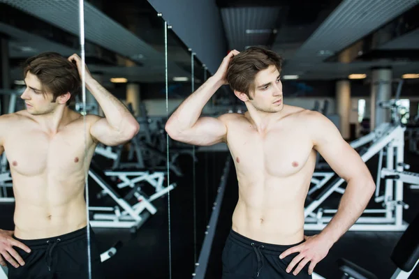 Young muscular sexy man workout in gym near the mirror shadows — Stock Photo, Image