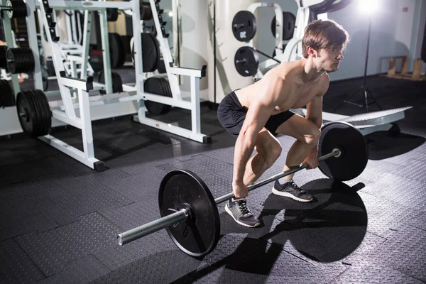 Jongeman buigen spieren met barbell in sportschool. Sport — Stockfoto