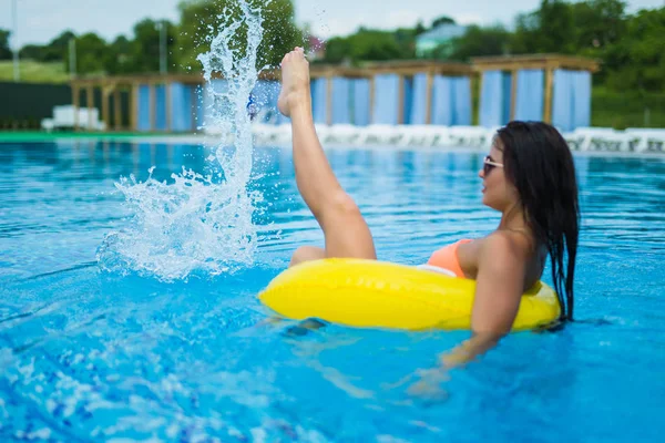 Genç güzel kadın kauçuk halka ile Yüzme havuzunda rahatlatıcı olduğunu.