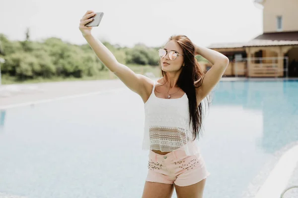 Retrato de menina bonita tirando uma selfie na piscina. Diversão de verão — Fotografia de Stock