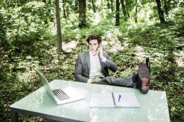 Ofis Masası yeşil park takım elbiseli adam rahat iş konuşmak cep telefonu başarılı iş bitmiş. İş kavramı.