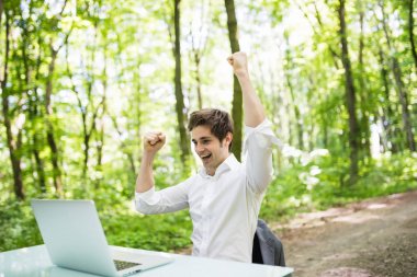 Mutlu çıktıktan iş adamı kaldırdı elleriyle kutlamak yeni anlaşma ile müşteri ya da Ofis Masası yeşil park laptop önünde harika bir haber. İş kavramı.
