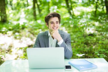 Ofis masaları yeşil park laptop çalışan genç yakışıklı serbest meslek sahibi. İş kavramı.