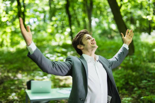 Zakenman met zijn armen wijd open in groen park voor zijn kantoor. Bedrijfsconcept — Stockfoto