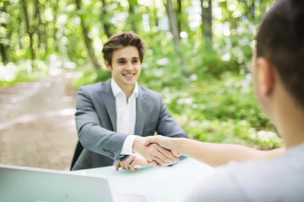 Менеджер у костюмі вітає рукостискання на співбесіді з новим робітником за його офісним столом у зеленому парковому лісі. Концепція бізнесу . — стокове фото