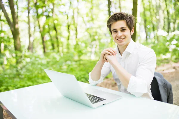 Feliz gerente guapo en camisa blanca trabajando en el portátil en el escritorio de la oficina en Green Park. Concepto empresarial . —  Fotos de Stock