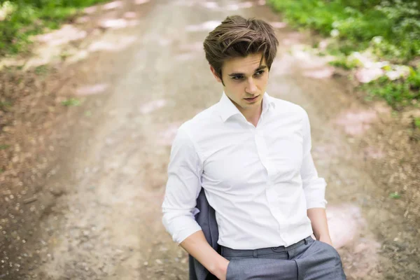 Hombre guapo en traje sentado en la silla de la oficina en la carretera en el bosque verde. Concepto empresarial — Foto de Stock