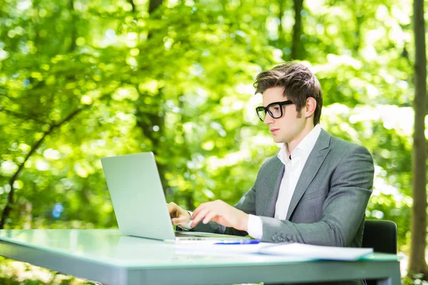 Retrato del hombre de negocios guapo que trabaja en el portátil en la mesa de la oficina en Green Park. Concepto empresarial . — Foto de Stock