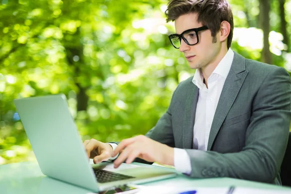 Giovane bel manager che lavora al computer portatile al tavolo dell'ufficio a Green Park. Concetto aziendale . — Foto Stock