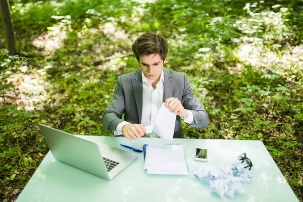 Giovane bell'uomo d'affari al tavolo da lavoro ufficio con computer portatile in carte da lavoro verde foresta lacrima. Concetto aziendale — Foto Stock
