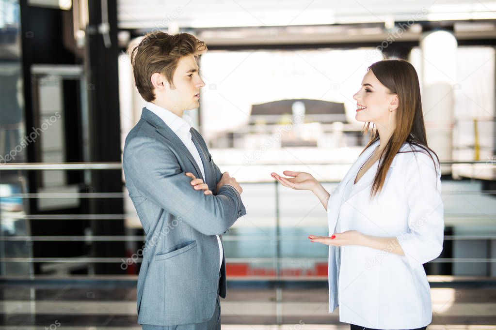 Smiling businesswoman telling something to her colleague in the office. Business man speak with business woman in office