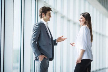 iş, ekip çalışması, ortaklık, işbirliği ve insanlar kavramı - iş adamları birbirlerine panoramik ofis pencere üzerinden konuşmak. İş adamı ve iş kadını ofiste