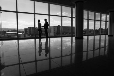 Silhouette işadamı ve Office büyük panoramik pencereler ile el sıkışan işkadını