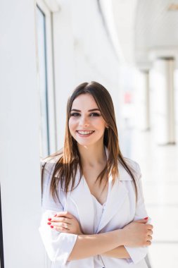 Takım elbise gülümseme panoramik pencerelere arka plan yakınındaki giyen portre işkadını.