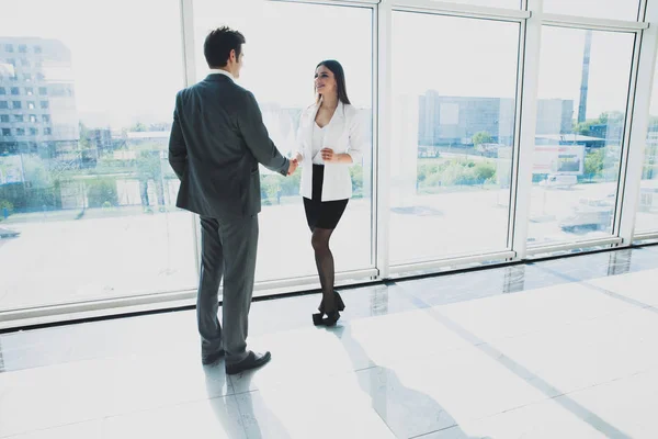 Двоє молодих бізнесменів і бізнес-леді стоять в сучасному офісі з панорамними вікнами . — стокове фото